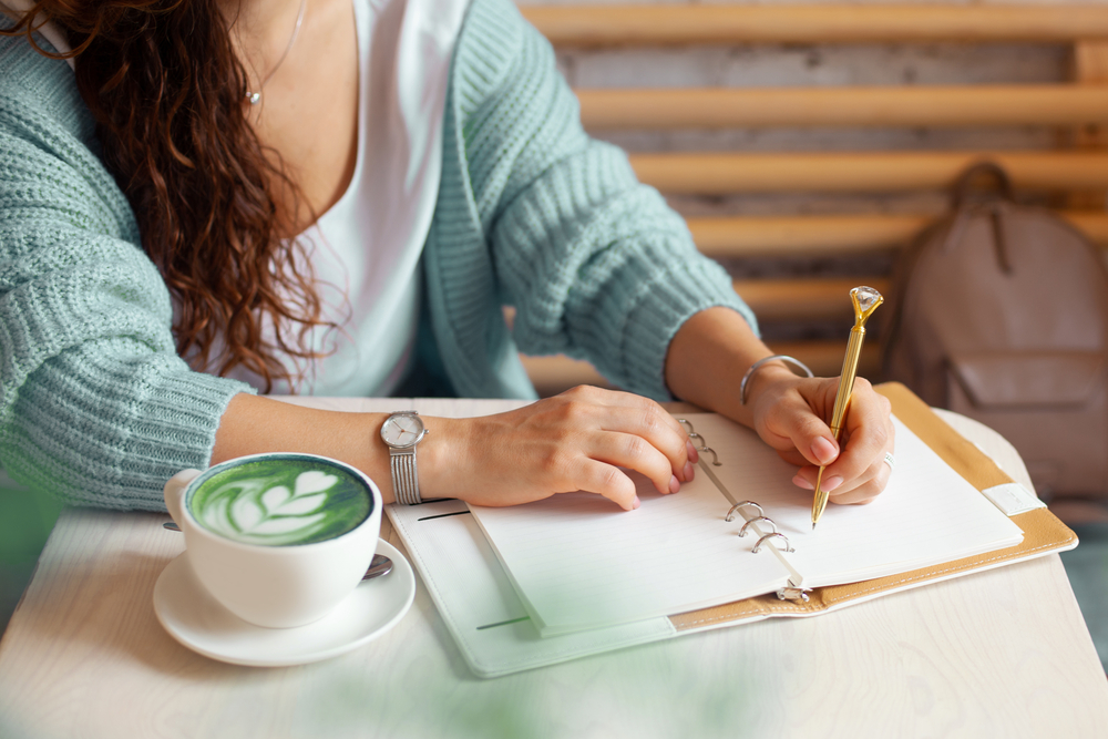 woman hand holding gold pen and writing notes with
